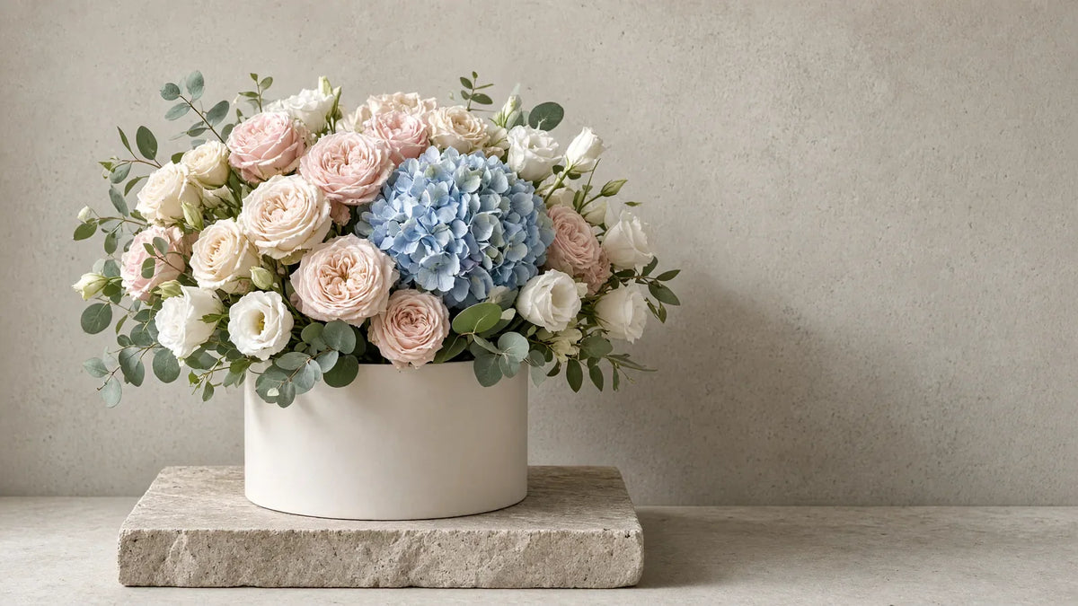 Flowerbox – okrągłe matowe pudełko z pudrowymi różami, hortensją i eustomą na jasnym betonie – IFIORA Warszawa